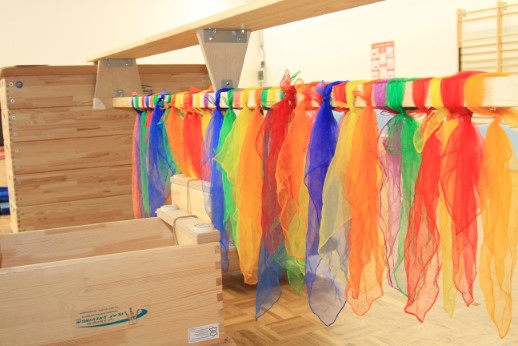 Bunte Tücher hängen im Bewegungsraum von einer Stange.